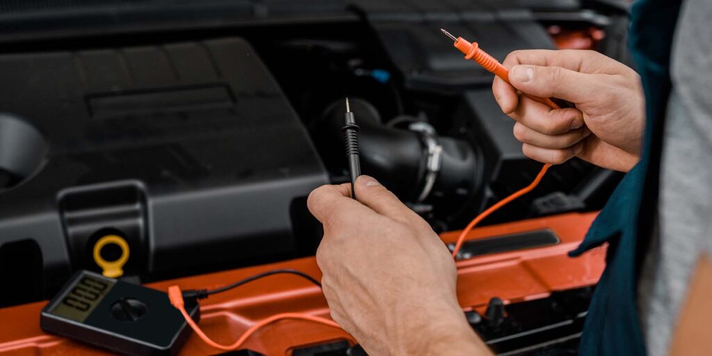 cropped-shot-of-auto-mechanic-with-multimeter-volt-75JAMKL.jpg